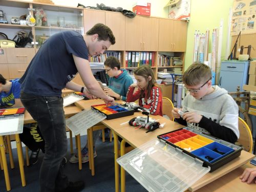 Uczniowie kl.6 skupieni na konstruowaniu robotów. Instruktor Planety Robotów daje im wskazówki.