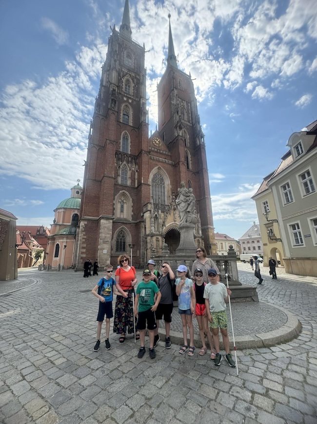 Cała klasa II na tle katedry rozświetlonej słońcem przebijającym przez chmury